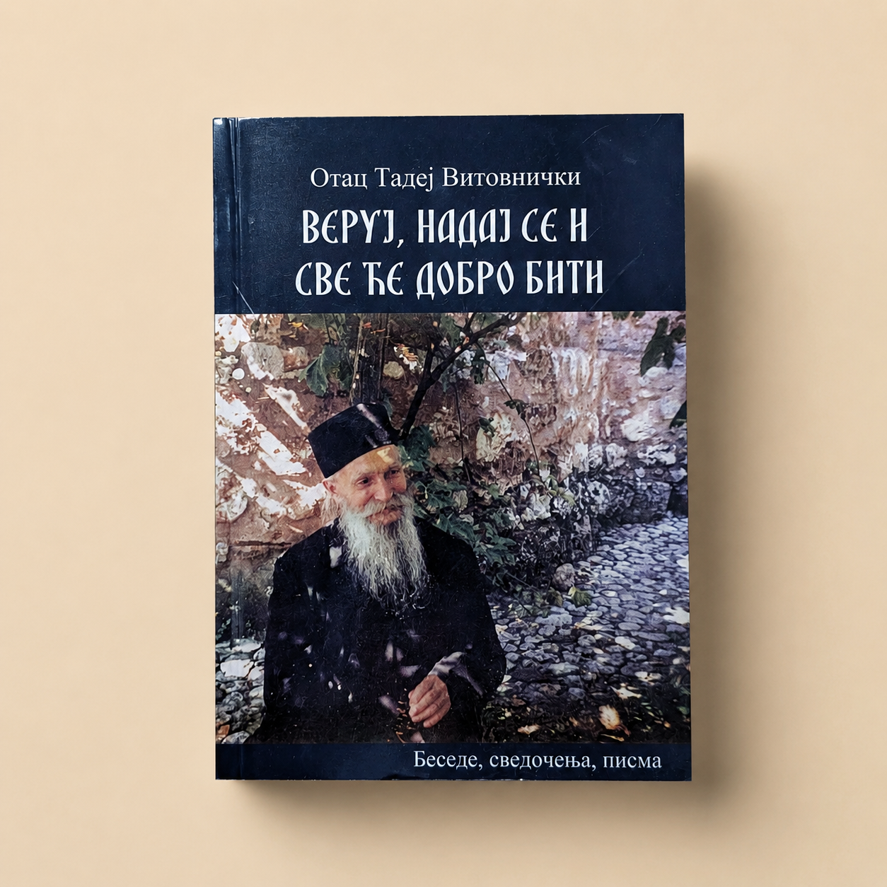 Buch „Vjeruj, nadaj se i sve će dobro biti“ von Otac Tadej Vitovnički in serbischer Kyrillisch-Schrift auf beigem Studiohintergrund.